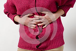 Closeup photo. a woman has a pain in her stomach, and holds her hands. Concept of female medicine. Digestive problems, gynecology