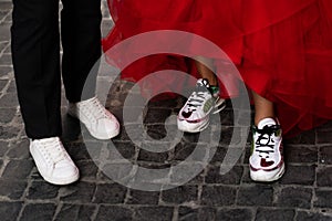 Closeup photo of woman and man legs in red dress, pants and shoes, stylish couple kissing during date,  over