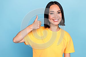 Closeup photo of young attractive cute girlish woman wear yellow t-shirt showing thumb up like product isolated on cyan