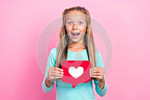 Closeup photo of young little pretty schoolkid girl open mouth excited positive hold red paper heart shocked isolated on
