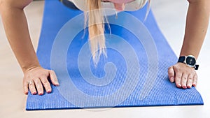 Closeup photo of young woman doing push ups on fitness mat at home