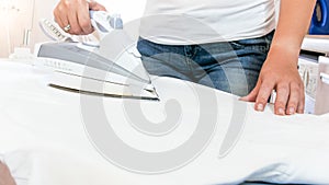 Closeup image of young woman ironing clothes with electric iron