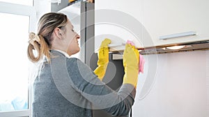 Closeup photo of young woman polishing metal handles on kitchen cupboards