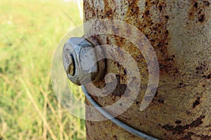 A closeup photograph of a silver bolt that is bolted onto a rusted steel pole