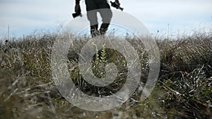 Closeup of a photographer`s foot whose silhouette goes beyond the horizon into defocus. A photographer walks across a