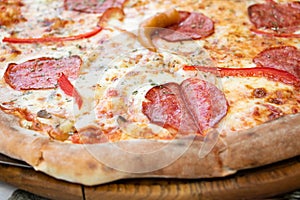 Closeup photography of fresh pizza, divided into slices. With pieces of sausage,tomatos,cheese and pieces of meat.Food background