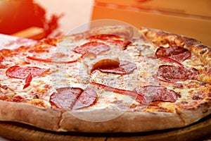 Closeup photography of fresh pizza, divided into slices. With pieces of sausage,tomatos,cheese and pieces of meat.Food background.