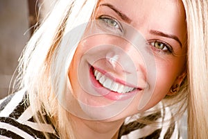 Closeup picture of beautiful blond young woman having fun happy smiling showing great dental whitening teeth