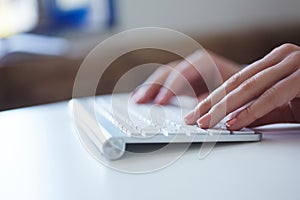 Closeup image of female hand typing on desktop computer keyboard.