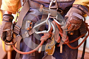 Rope access worker wearing full safety harness inspecting clocking Karabiner on a chair prior to abseiling photo