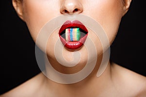 Closeup picture of woman`s lips holding sweeties