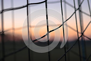 A closeup picture of a soccer net with a sunset sunrise in the background. detail ,sport, future, dreams, game football, goal, foo