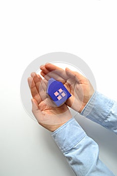 Woman hands holding paper house on white background. Mortgage concept