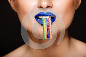 Closeup picture of woman`s colorful lips holding sweeties.