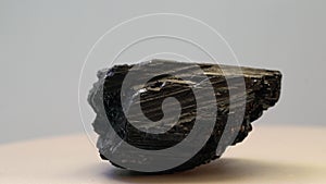 Closeup of a piece of wolframite spinning on a white platform