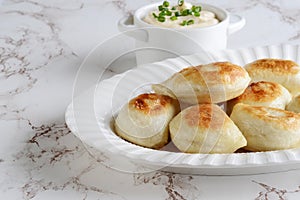 Closeup pierogies on a platter with sour cream and spring onions