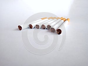 Closeup of a pile of cigarettes over white background. The tobacco can cause numerous damages to the organism