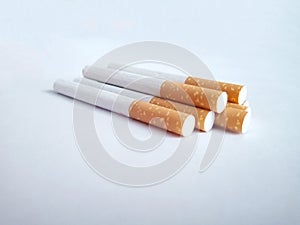 Closeup of a pile of cigarettes over white background. The tobacco can cause numerous damages to the organism