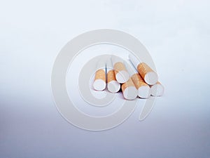 Closeup of a pile of cigarettes over white background. The tobacco can cause numerous damages to the organism