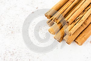 Closeup of a Pile of Cinnamon Sticks over White Speckled Background with Copy Space