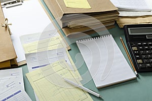 Closeup of pile document folders, bills, notebook,pen, calculator on the desk.Working process