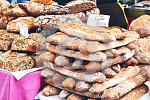 Closeup of pile of fresh French artisan sourdough baguettes and whole grain cereal and pumpkin seed breads London street