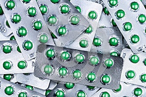 Closeup pile of round green sugar coated tablet pill in blister pack. Combine pill for relief cough. Pharmaceutical product.