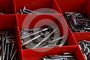 Closeup of a pile of screws in a red box.