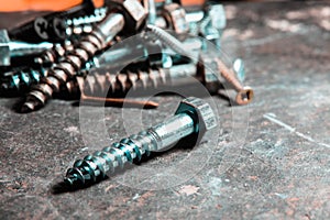 Closeup of a pile of screws on the table with a blurry background