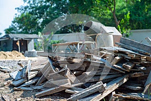 Closeup pile of useless wood at the construction site with blurred concrete mixer in background