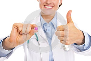 Closeup on pill in hand of smiling doctor woman