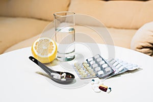 Closeup pills, lemon and glass of water on table
