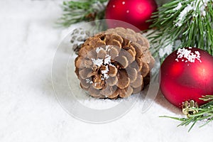 Closeup of a Pine Cone on Snow with Pine Tree Branch and Ornaments