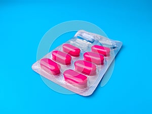 Closeup of pink antibiotic pills in gray packaging isolated on a blue background