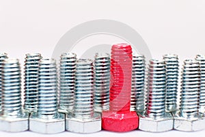 Closeup of pink bolt n a group of galvanized metallic screws. Leadership, individuality, dissimilarity concept photo