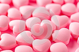 Closeup of pink candy hearts and sweets in shape of love symbol on pink background, for Valentine's day