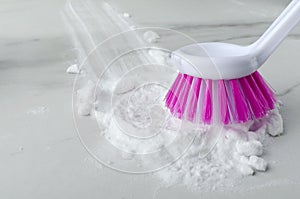 Closeup of pink cleaning brush and baking soda on the white table.Empty space