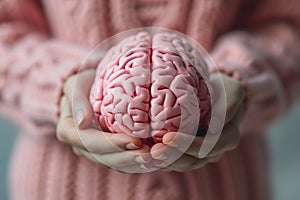 closeup pink human brain model in female hands. mental health or disorder concept