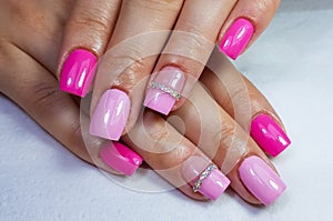 Closeup of pink manicure on long square-shaped nails under the lights