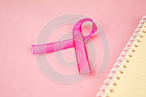 Closeup of pink ribbon besides a notebook