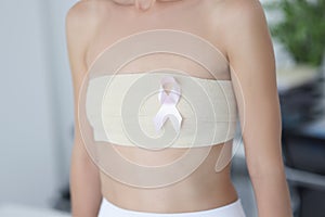 Closeup of pink ribbon on patient chest with elastic bandage