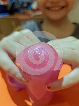 closeup pink shiny slime with young girl smiling while playing