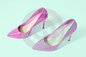 Closeup pink women patent leather shoes isolated on green background. Stilettos shoe type. Summer fashion and shopping concept.