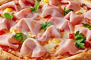 Closeup of pizza with ham, quail eggs, tomatoes and greens on melted mozzarella