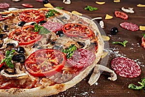 Closeup of pizza with salami, tomatoes and olives