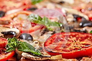 Closeup of pizza with salami, tomatoes and olives