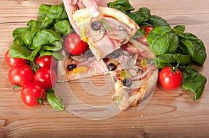 Closeup of pizza with tomatoes, cheese, basi and woman's handsl on wooden background