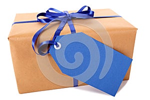 Closeup of plain brown paper package or parcel, blue gift tag or label isolated on white background