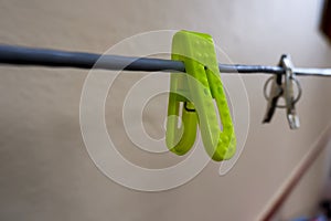 Closeup of a plastic green clothespin on a rope under the lights with a blurry background