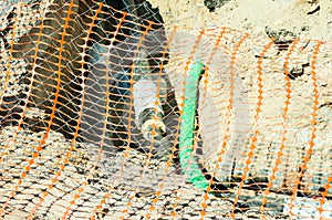 Closeup of plastic orange safety net used as security fence on the street district heating pipeline system excavation site to prot